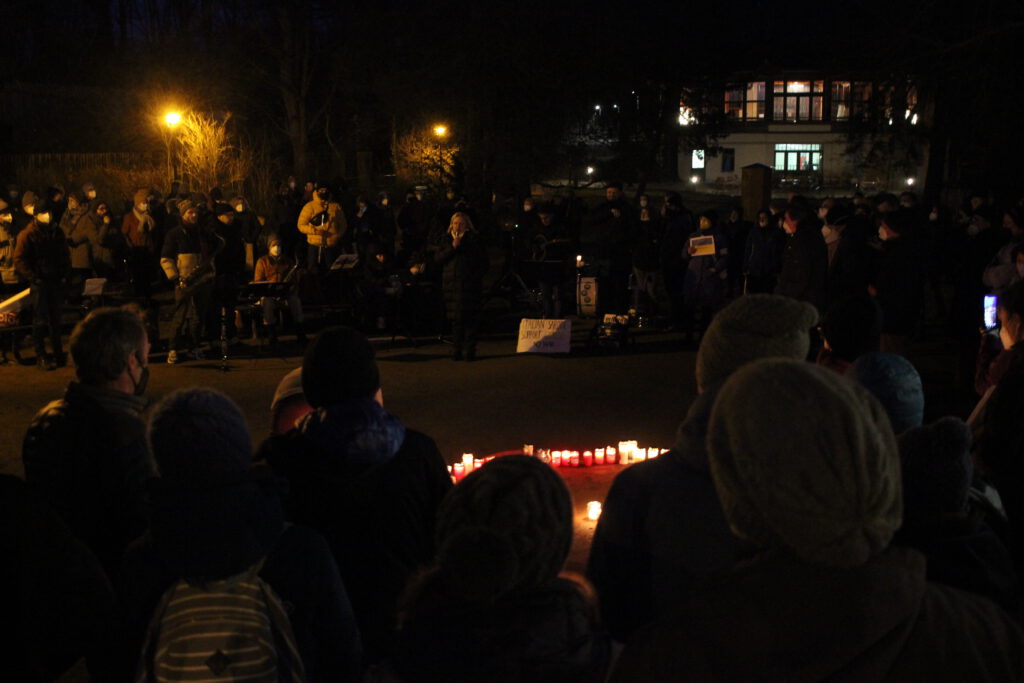Die Menschenmenge lauscht dem Vortrag der Referentin über die Zustände in der Ukraine. Kerzen stehen in der Mitte des Platzes.